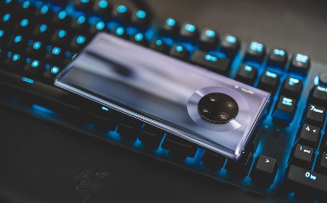 雪原上的一台摄影机架在三脚架前，远处是低垂的云层与松林，纪录片拍摄现场